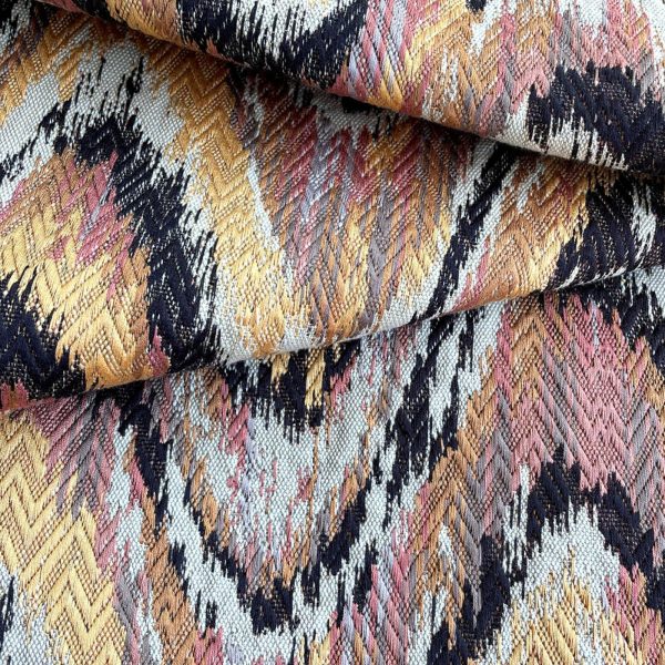 A close up of a flame stitch fabric in shades of pink and gold