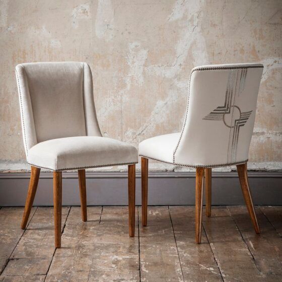 Two luxurious, handcrafted dining chairs with a hand embroidery design on the back