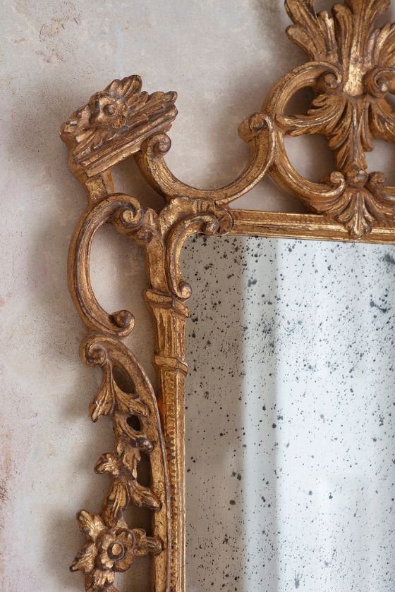 An ornate, antique style mirror in a hand gilded gold finish.