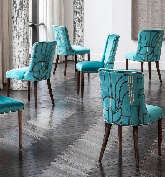 A collection of beautifully upholstered dining chairs in a luxurious aquamarine silk velvet with an elegant Art Deco inspired embroidery design on the back