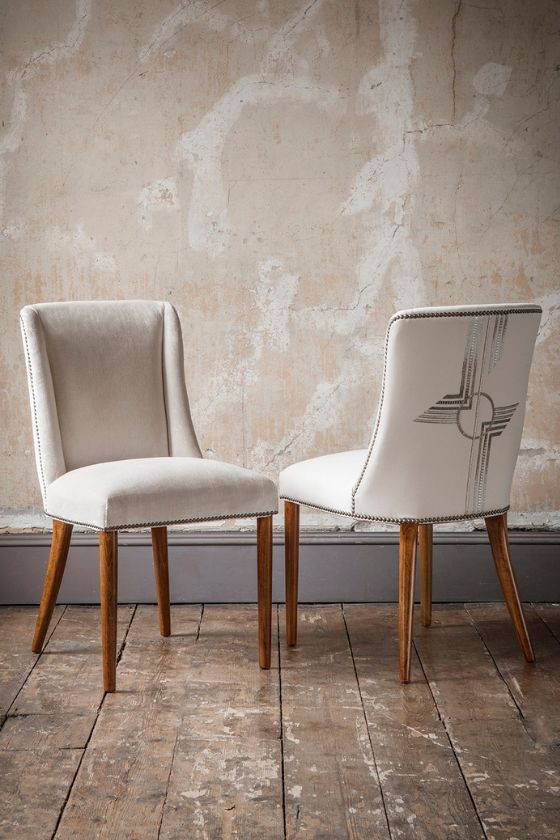 Two luxurious upholstered dining chairs with embroidery on the back