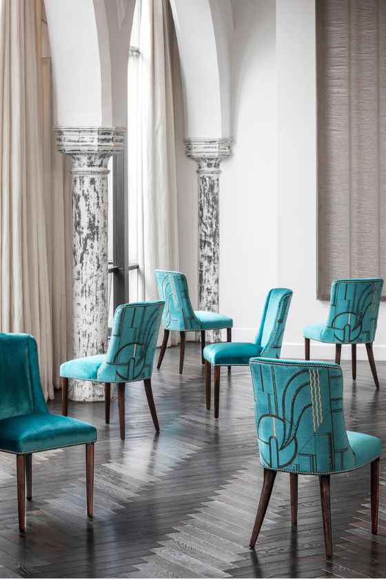 A group of luxurious upholstered dining chairs in an aquamarine silk velvet